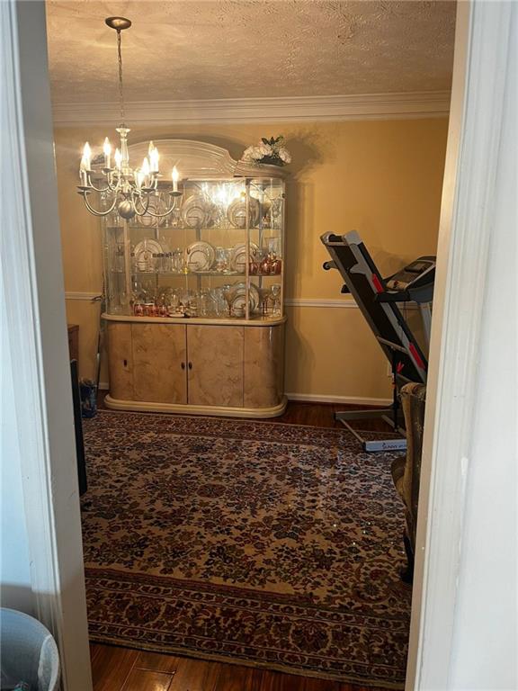 interior space with dark hardwood / wood-style floors, a textured ceiling, a chandelier, and ornamental molding