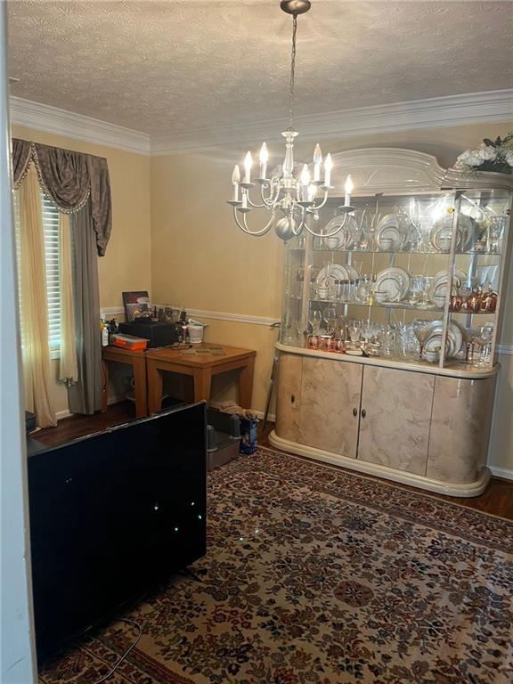 carpeted dining space with a textured ceiling, a notable chandelier, and crown molding