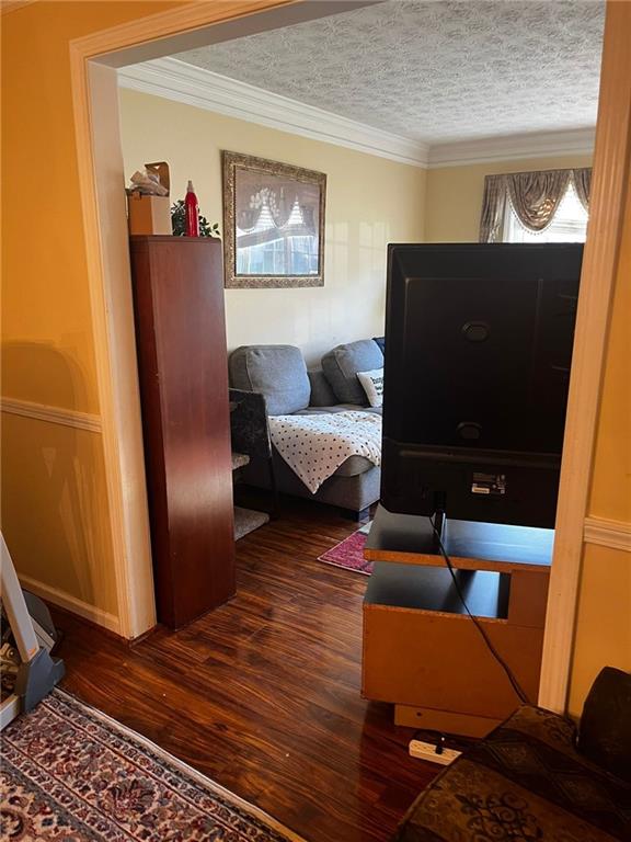 bedroom with dark hardwood / wood-style flooring, a textured ceiling, and crown molding