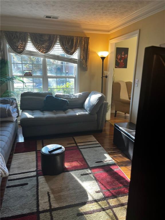 living room featuring dark hardwood / wood-style flooring, a textured ceiling, and crown molding