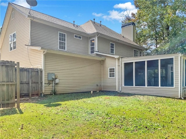 rear view of house featuring a sunroom and a yard