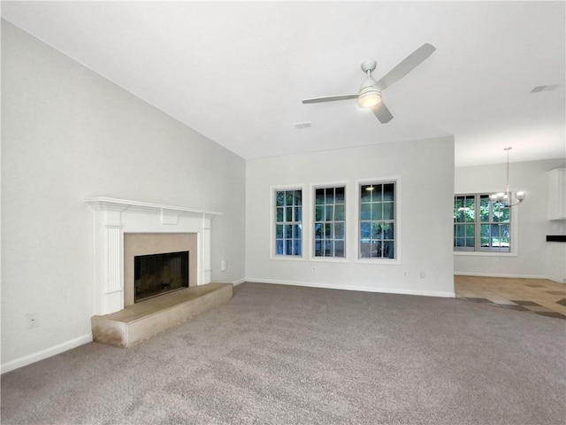 unfurnished living room with ceiling fan with notable chandelier, lofted ceiling, a high end fireplace, and carpet floors