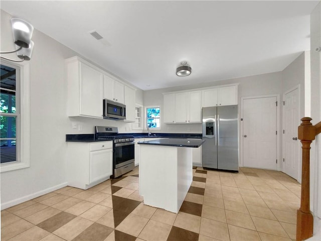 kitchen with light tile patterned floors, sink, white cabinetry, appliances with stainless steel finishes, and a center island