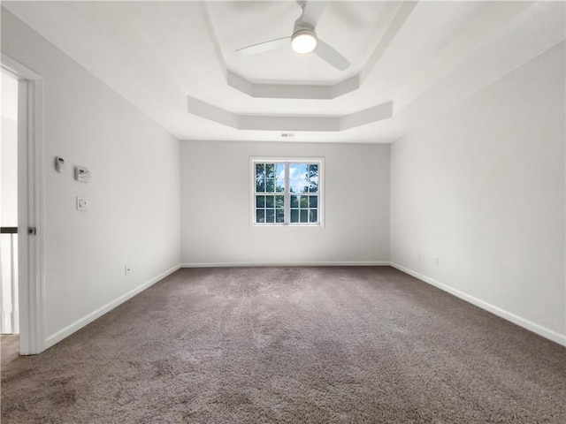 empty room featuring ceiling fan, a raised ceiling, and carpet flooring