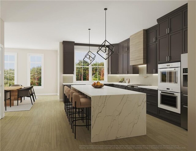 kitchen featuring tasteful backsplash, double oven, pendant lighting, a center island, and light hardwood / wood-style floors