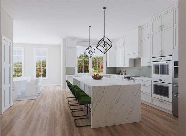 kitchen featuring white cabinetry, decorative light fixtures, and light wood-type flooring