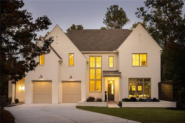 view of front of house featuring an attached garage, a standing seam roof, metal roof, a shingled roof, and driveway