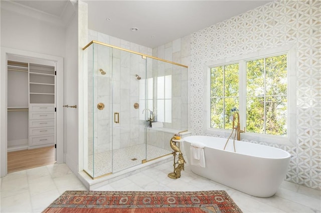 bathroom with a freestanding bath, a spacious closet, and a shower stall