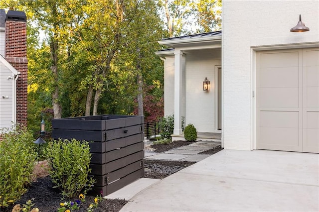 entrance to property with brick siding, metal roof, a standing seam roof, a garage, and driveway