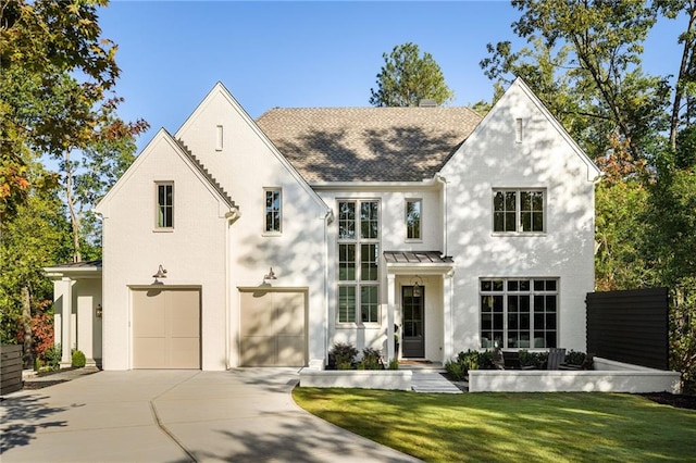 view of front of house with an attached garage, metal roof, a standing seam roof, a shingled roof, and driveway