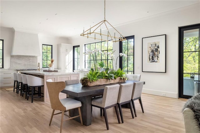 dining room with plenty of natural light, ornamental molding, and light wood-style floors