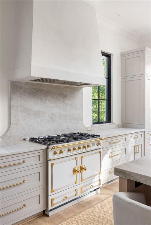 kitchen with light wood-style floors, backsplash, light countertops, and custom exhaust hood