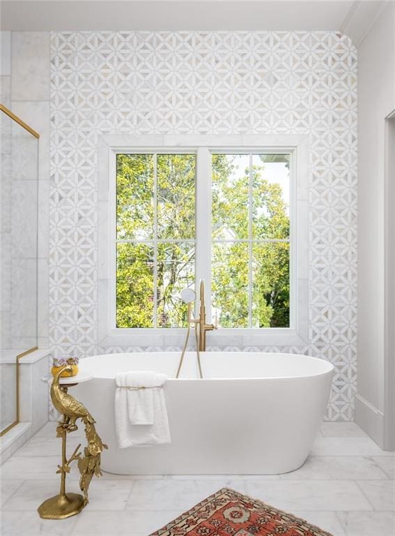 bathroom with a freestanding bath, a wealth of natural light, and marble finish floor