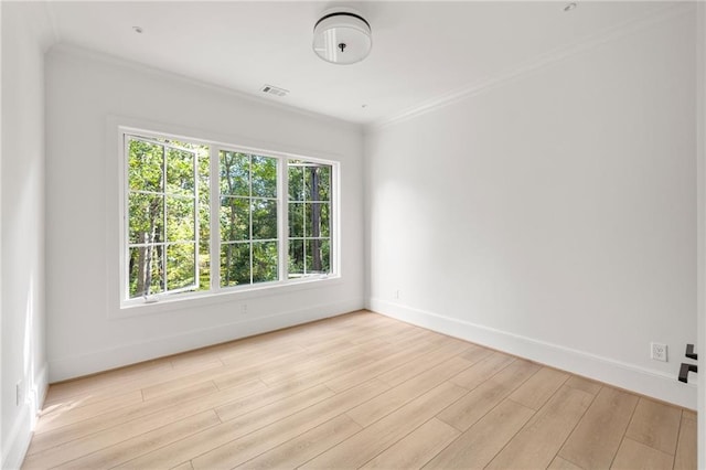 unfurnished room with light wood finished floors, ornamental molding, baseboards, and visible vents