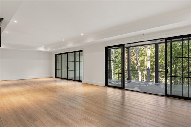 unfurnished room featuring light wood-type flooring, recessed lighting, baseboards, and a raised ceiling