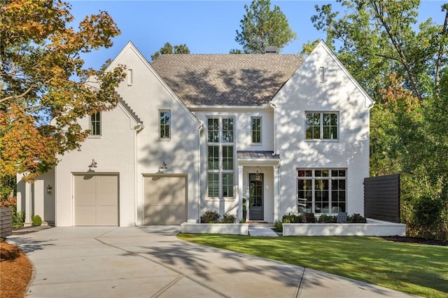 view of front facade with a garage, a front yard, concrete driveway, metal roof, and a shingled roof