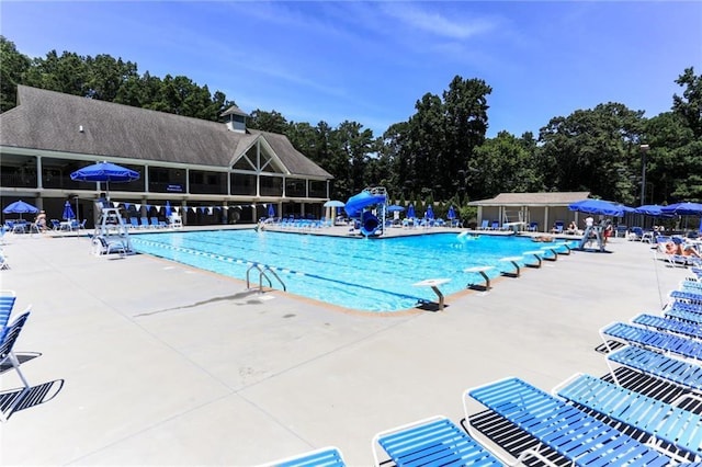 view of swimming pool with a water slide and a patio area