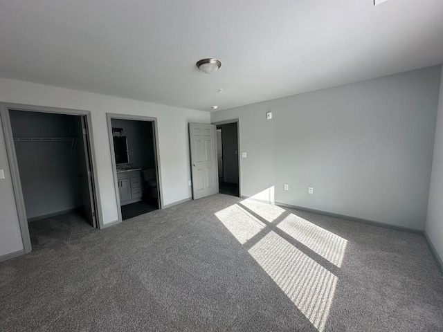 unfurnished bedroom with carpet flooring, ensuite bath, a closet, and a spacious closet