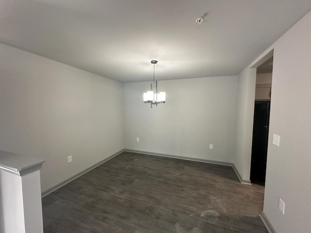 unfurnished dining area featuring dark wood-type flooring and a notable chandelier