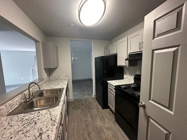 kitchen with sink, light stone counters, black appliances, light hardwood / wood-style floors, and white cabinets