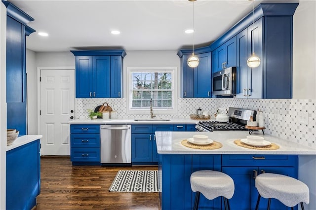 kitchen featuring sink, light stone counters, decorative light fixtures, appliances with stainless steel finishes, and a kitchen breakfast bar