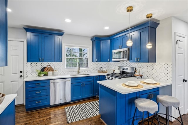 kitchen featuring sink, blue cabinetry, a breakfast bar, stainless steel appliances, and decorative light fixtures