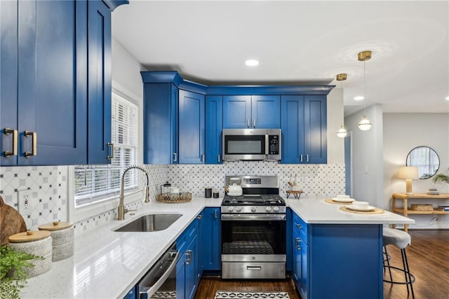 kitchen with a kitchen bar, blue cabinets, sink, decorative light fixtures, and appliances with stainless steel finishes