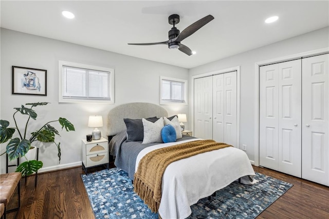 bedroom with dark wood-type flooring, two closets, and ceiling fan