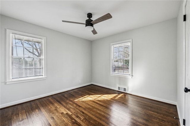 empty room with ceiling fan, plenty of natural light, and dark hardwood / wood-style flooring