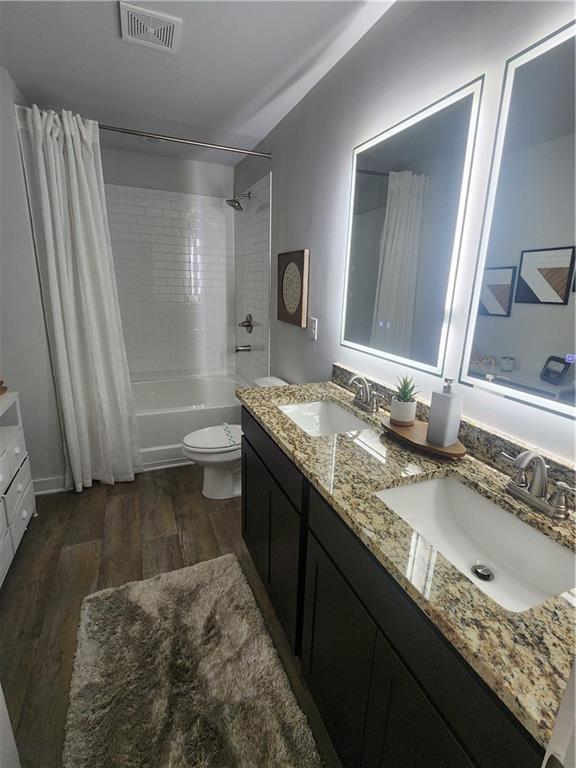 4839 Station Ln, Union City, GA 30349 - bathroom with wood finished floors, shower / bath combination with curtain, toilet, and double vanity