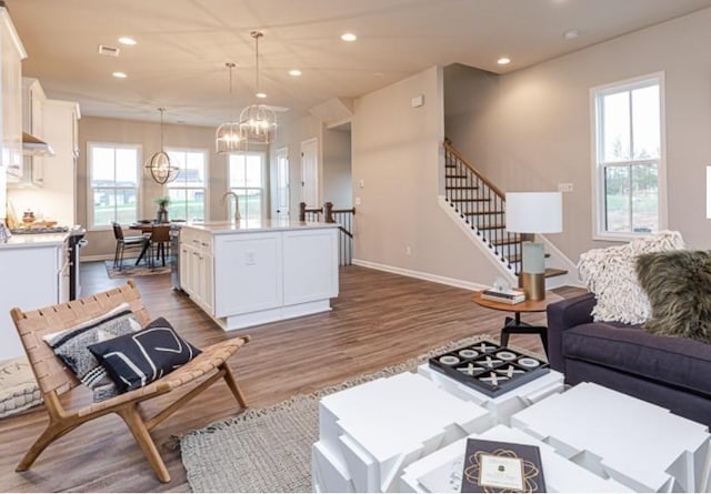 living room featuring wood finished floors, baseboards, an inviting chandelier, recessed lighting, and stairs