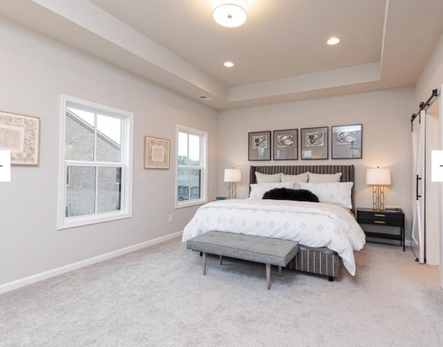 bedroom with carpet flooring, baseboards, a raised ceiling, and a barn door