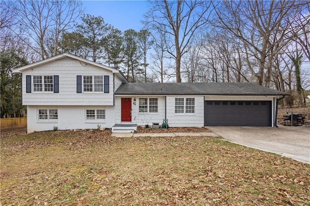 tri-level home with a front yard, driveway, an attached garage, and fence