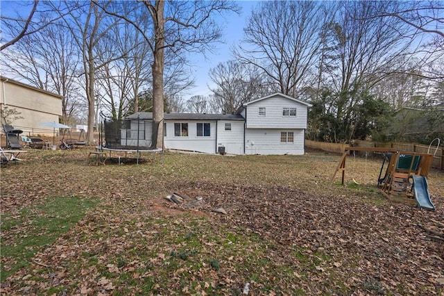 back of house featuring a trampoline, a playground, and fence