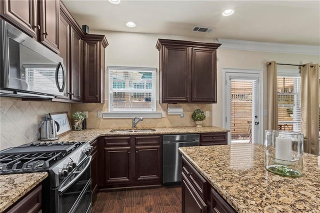 kitchen featuring dark wood-style floors, stainless steel appliances, visible vents, a sink, and dark brown cabinets