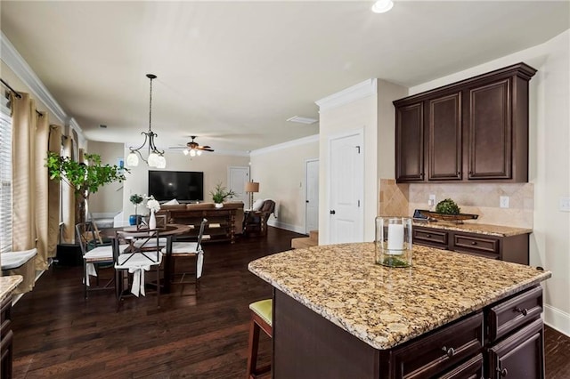 kitchen featuring a kitchen island, open floor plan, dark brown cabinets, backsplash, and decorative light fixtures