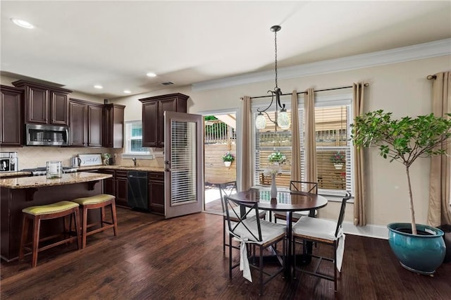 kitchen with light stone counters, pendant lighting, stainless steel microwave, and dark brown cabinets