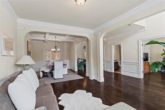 living room with arched walkways, a wainscoted wall, coffered ceiling, dark wood-style floors, and beamed ceiling