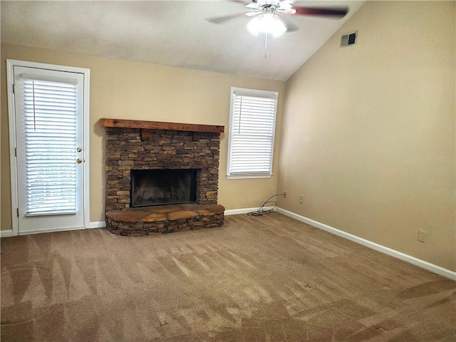 unfurnished living room with lofted ceiling, carpet flooring, a wealth of natural light, and a stone fireplace