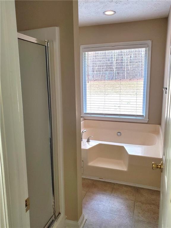 bathroom featuring plus walk in shower and a textured ceiling