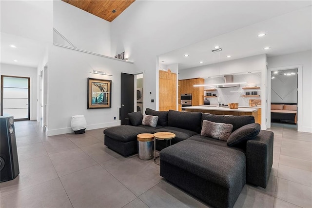 tiled living room featuring a towering ceiling and stacked washing maching and dryer