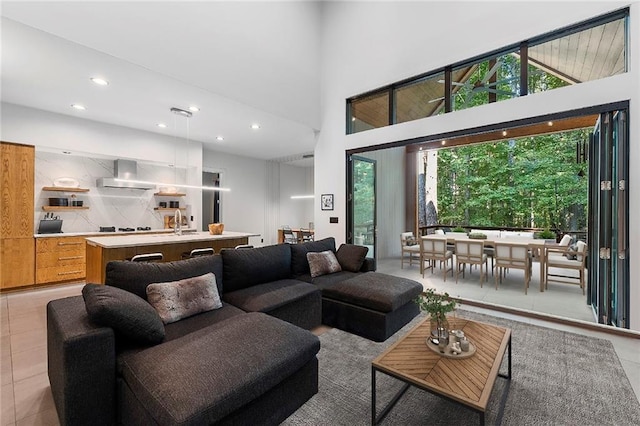 tiled living room with plenty of natural light, a towering ceiling, and sink