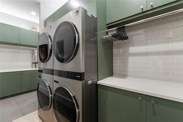 laundry area featuring cabinets, stacked washer and dryer, and light tile patterned floors