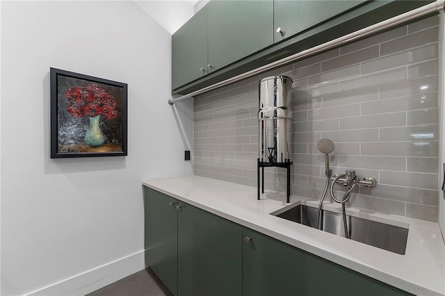 kitchen with tasteful backsplash, green cabinetry, and sink