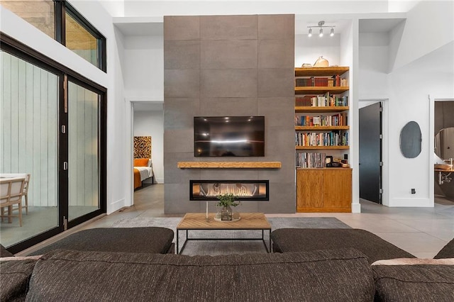 living room featuring a towering ceiling, a fireplace, and built in features