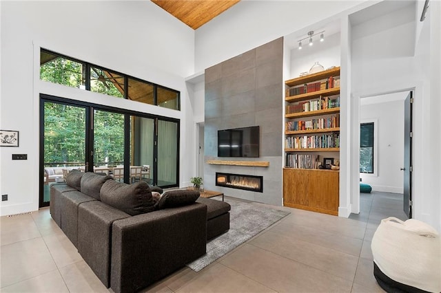 tiled living room featuring a towering ceiling and a fireplace