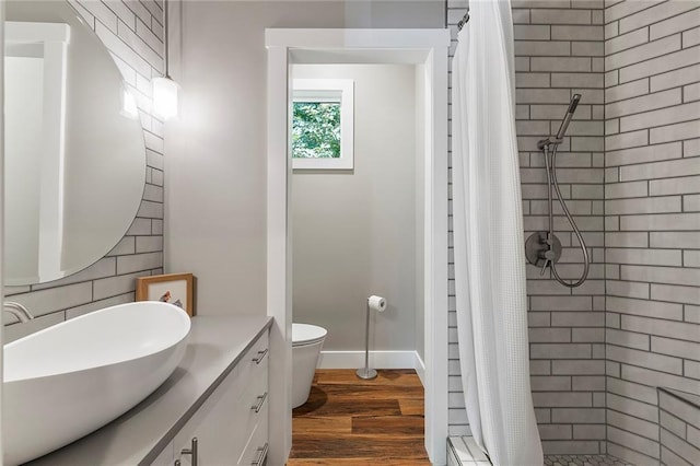 bathroom with hardwood / wood-style flooring, vanity, toilet, and curtained shower