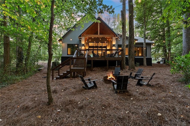 back house at dusk featuring a deck and a fire pit