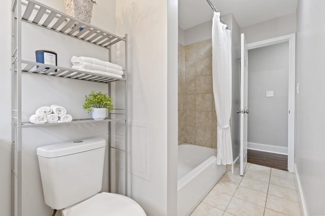 bathroom featuring shower / bathtub combination with curtain, tile patterned flooring, and toilet