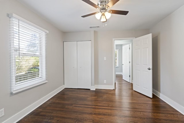 unfurnished bedroom featuring dark wood-type flooring, a closet, and ceiling fan